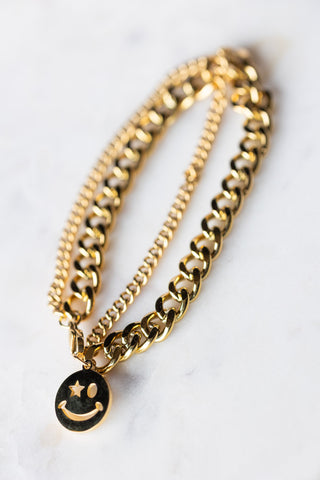 The Waterproof Wink Face Gold Chain Bracelet on a white surface.