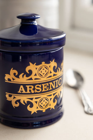 Close-up shot of the What's Your Poison - Arsenic Jar next to a silver teaspoon.