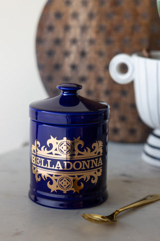 The What's Your Poison - Belladonna Jar on a kitchen counter with a spoon, plant pot and wooden serving board.