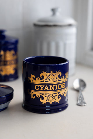 The What's Your Poison - Cyanide Jar shown with it's lid off next to a silver teaspoon.