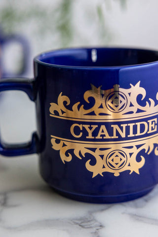 A close-up shot showing the gold lettering on the What's Your Poison - Cyanide Mug.