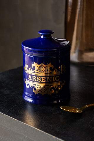 The What's Your Poison - Arsenic Jar displayed on a black surface with a spoon.