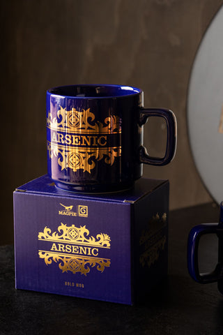 The What's Your Poison - Arsenic Mug displayed on a table on top of the box.