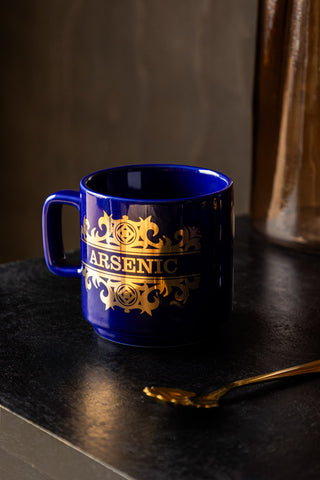 The What's Your Poison - Arsenic Mug styled on a dark table with a gold spoon.