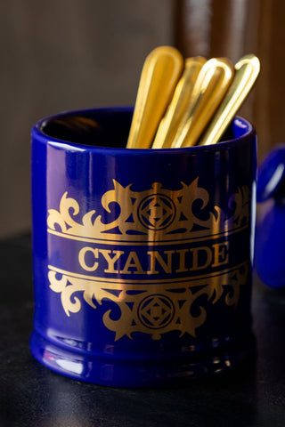 Close-up of the What's Your Poison - Cyanide Jar with the lid off and some gold cutlery inside.