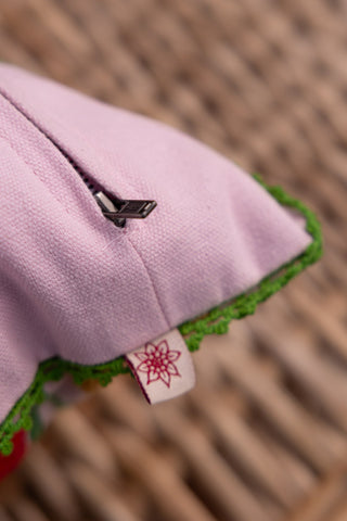 Close-up of the corner of the Wild Embroidered Cushion, showing the tag and zip.