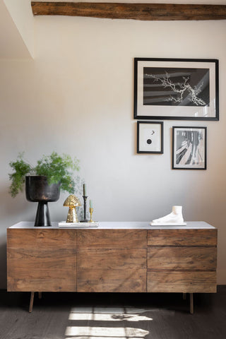 The Wood & Marble Barcelona Sideboard styled with various home accessories on and some art prints on the wall above.