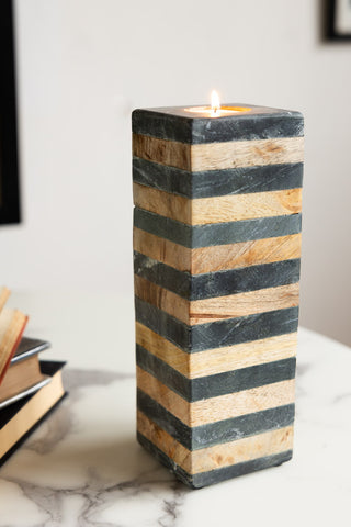 The Wood & Slate Tealight Holder on a table with some books, styled with a lit candle inside.