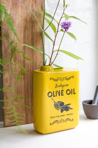 The Italiana Yellow Olive Oil Vase styled on a kitchen counter with a flower.