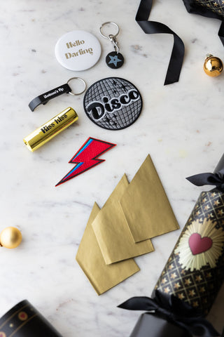 The contents of the Set Of 6 You've Got To Have Faith Christmas Crackers styled on a table with some of the crackers, baubles and ribbon.