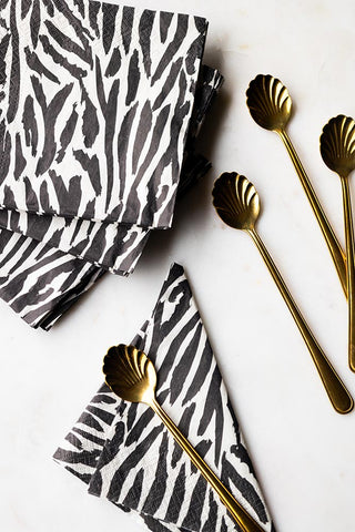 The Zebra Print Napkins - Pack Of 20 styled on a light surface with some gold spoons.