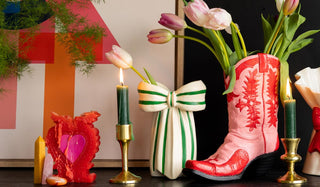 A sideboard styled with colourful vases, flowers, candles, crystals and an art print.