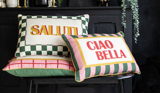 The Ciao Bella, Saluti and Merci cushions displayed together on a bench in front of a sideboard.