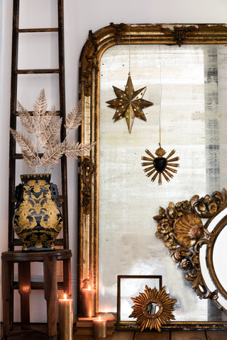 A beautiful vintage style setting with a large ornate mirror, wooden ladder shelf and stool. Styled on the pieces were vintage decorations and vases.