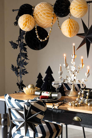 Lifestyle image of the Set Of 2 Ivory Honeycomb Ball Decorations hung on a table clamp above a black and white table look.