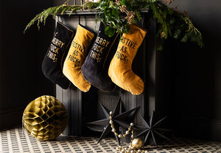 4 stockings on a dark fireplace. The stockings alternate between black and gold.