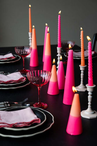 Tablescape with plates, napkins, cutlery and glassware styled with various lit colourful candles.