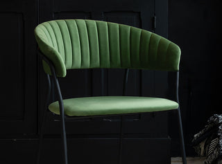 Green curved back dining chair in a dark kitchen which further emphasises the beautiful green hue of the dining chair.