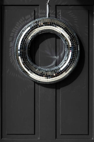 The Round Mirror Ball Wreath styled hanging on a black door.