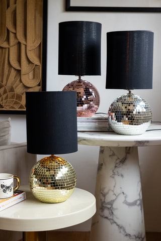 Three beautiful disco ball table lamps in gold, silver and pink on two side tables in a living room. 