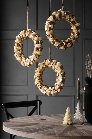 Three Double-sided Ivory Bell Christmas Wreaths hanging above a table decorated with Christmas items.