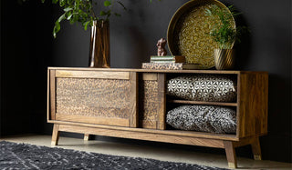 The Leopard Print TV Unit with one door open, styled with various home accessories and greenery, in front of a black wall.