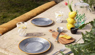 An outdoor table with various dining accessories styled on.