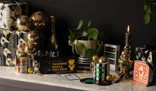 Various Rockett St George gifting products styled together on a marble sideboard with lit candles, wrapped presents, fairy lights and greenery.