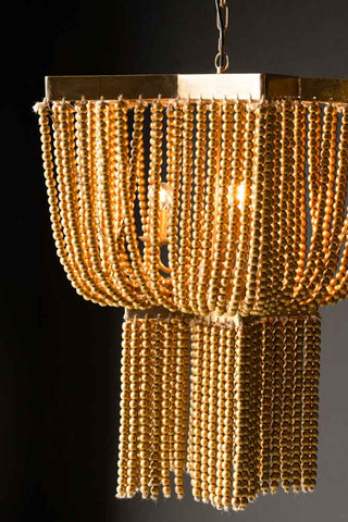 Close-up shot of the Gold Star Shaped Beaded Statement Chandelier Light switched on in front of a black wall.