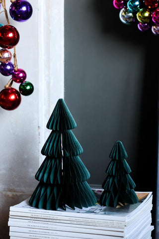 Two green paper trees stacked on magazines next to a fireplace.