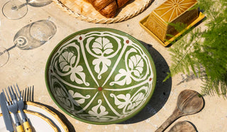 An outdoor tablescape with a patterned bowl, butter dish, cutlery, plates and glassware,