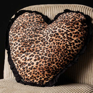 A beautiful leopard print heart shaped cushion with a black ruffled edge on a cream armchair.