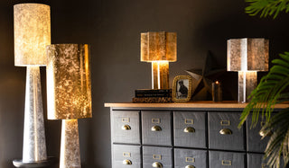 The Gold and Silver Leafed Effect Floor Lamps and Star Table Lamps styled together on/around a black sideboard with various home accessories and plants.