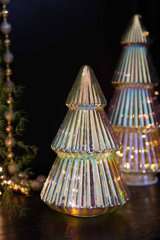 The Medium Glass Christmas Tree With LED Lights styled with the large version in the background, with some greenery, beads and fairy lights.