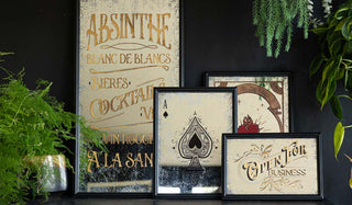 A selection of decorative mirrors styled on a sideboard leaning against a black wall with various greenery.