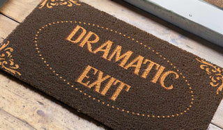 The Dramatic Exit Doormat styled on the floor by an open door.