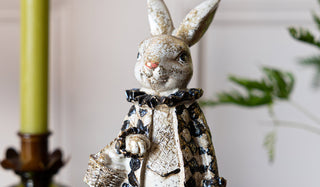 A rabbit ornament styled with a plant and candle in the background.