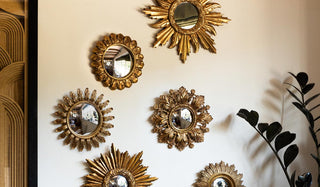 Some of the Set Of 9 Assorted Ornate Gold Framed Mirrors displayed on a neutral wall with a framed artwork, next to a plant.