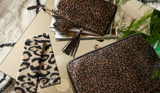 Various new Rockett St George leopard print accessories, styled on a table with magazines and greenery.