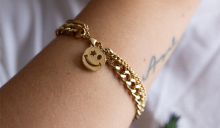 A smiley face chain bracelet on a model's arm.