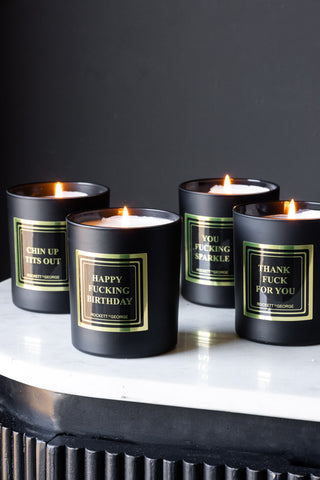 Four slogan candles lit and displayed on a white surface.