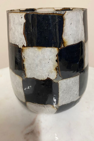 Side view of the black and white vase with cracks and scratches.