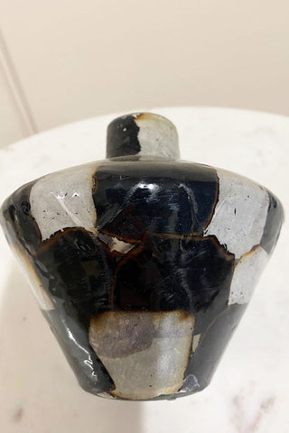 Side view of the black and white crackled vase. You can see the damage of the vase.