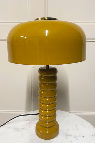 Side view of the mustard lamp on a white table. You can see some minor scratches.