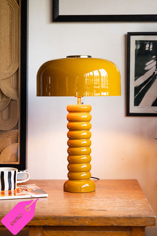 Mustard yellow vase on a wood sideboard cabinet.