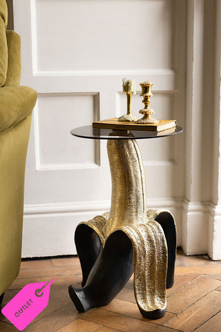 Black and gold Banana Side Table in a modern living room setting. In the bottom left hand side is a pink label that says - outlet- to denote that this is a sample piece.