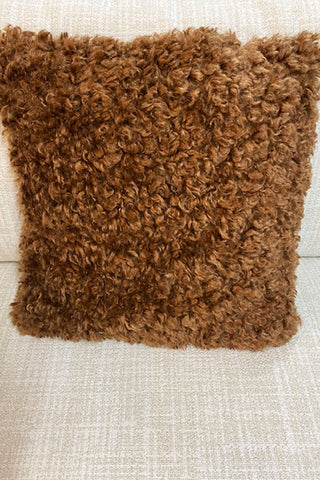 Brown fluffy cushion on a white chair