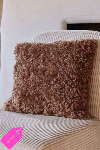 brown sheekskin effect fluffy cushion on an armchair.