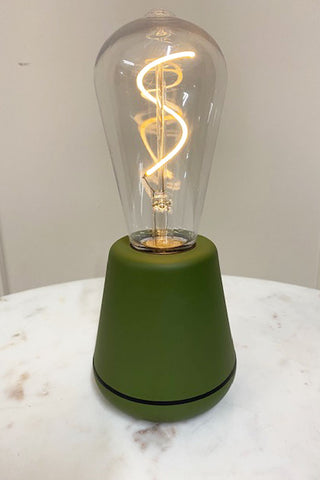 A green cable-free light with an exposed bulb and lit filament. 