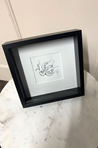 A beautiful framed 'I love you' bird art print that is sat on a white marble table.